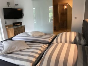 A hotel room with two beds, a flat-screen TV mounted on the wall, and a wooden cabinet.