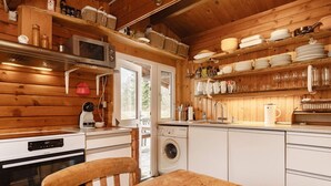 Eine gemütliche Küchenzeile in einer Holzhütte, mit Mikrowelle, Waschmaschine und Esstisch mit einer Schüssel.