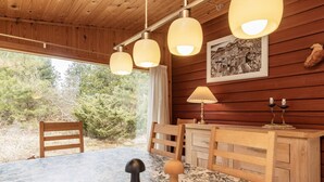Ein Holzhütten-Interieur mit Esstisch, Stühlen und Pendelleuchten.