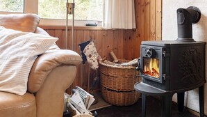Ein gemütliches Zimmer mit einer Couch, einem Korbwäsches und einem Kaminofen.