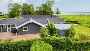 A modern house with a sloped roof, solar panels, and a wooden deck.