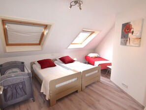Un dormitorio con dos camas, una cuna y tragaluces.