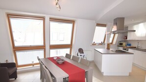 A modern kitchen with white cabinets, a built-in stove, and a microwave. - Apartment in a Central Location (Blankenberge)