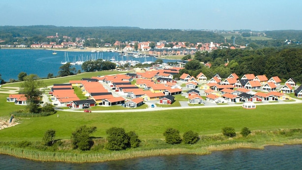 En kystlandsby med røde tage, en lysthavn og en sø.