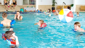 Ein Hallenbad mit mehreren Bahnen, einem Rettungsschwimmerstuhl und einem großen Strandball.