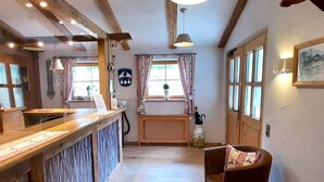 A reception area with a wooden counter, a reception desk, a chair, a rug, and a window with curtains.