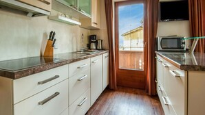 A compact kitchen with white cabinets, a microwave, and a coffee maker. - Apartment in Hainzenberg Near Ski Slopes (Hainzenberg)