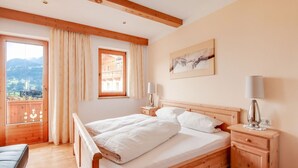 A bedroom with a wooden bed, two bedside tables, a window with curtains, and a painting on the wall. - Apartment in Hainzenberg Near Ski Slopes (Hainzenberg)