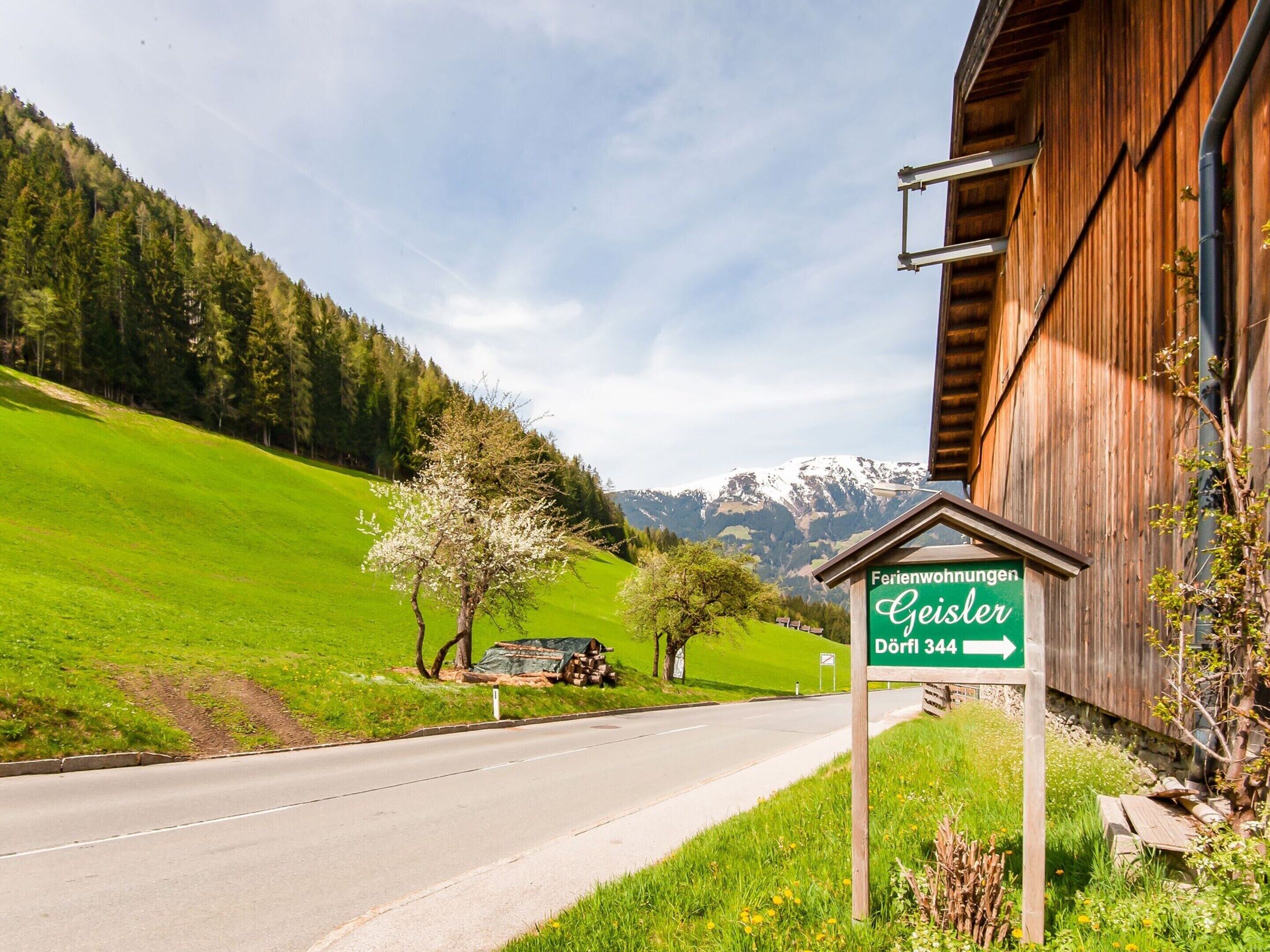 A sign for 'Ferienwohnungen Geisler' with a road leading to a wooden building.