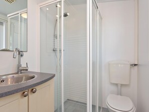 A modern bathroom with a glass-enclosed shower, a white toilet, and a granite countertop sink. - Lovely, Fully Furnished Chalet for 4 People (Goedereede)