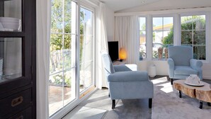 Uma sala de estar moderna com grandes janelas, lareira e área de jantar com uma mesa de centro de madeira.