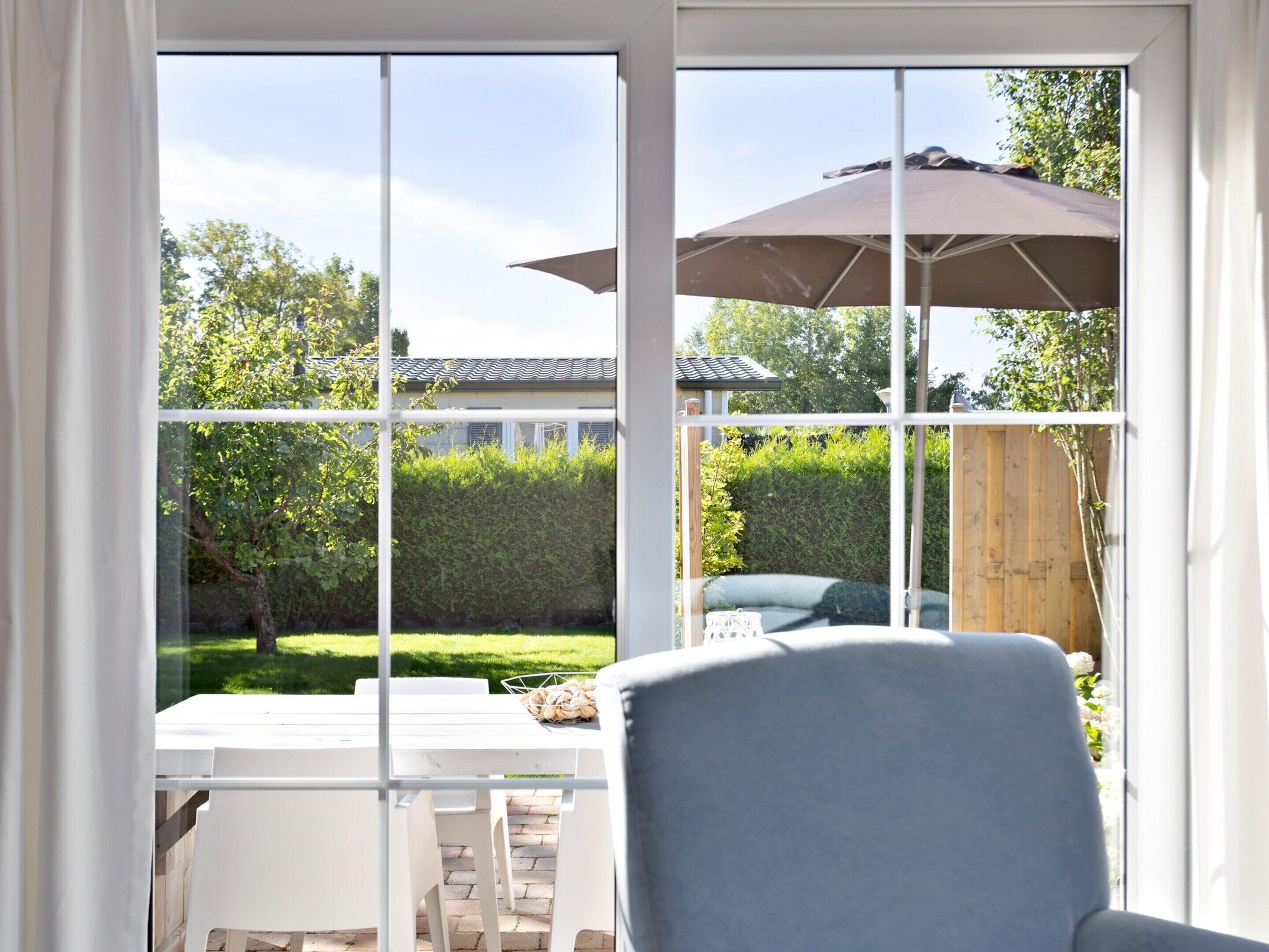 A room with a large window, a table, chairs, and a grey armchair.