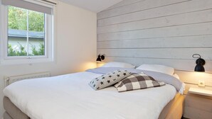 Quarto com uma cama, duas luminárias de apoio, uma janela e um radiador.