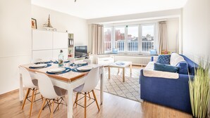 Una sala de estar moderna con comedor, ventanas amplias y vistas a la ciudad.
