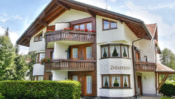 A multi-story building with a white textured exterior, wooden balconies, and a sign that reads "Bärenbush". - Barenhusli No. 7 (Titisee-Neustadt)