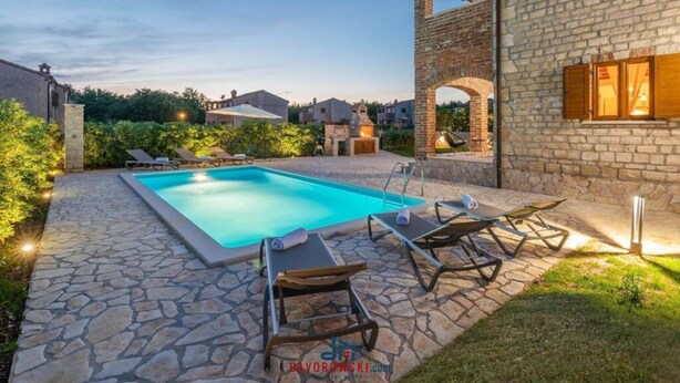 Une piscine rectangulaire, dotée de chaises longues et bordée d’un chemin en pierre.
