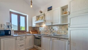 Une cuisine avec des meubles blancs, un four encastré et une fenêtre donnant sur un beau paysage.