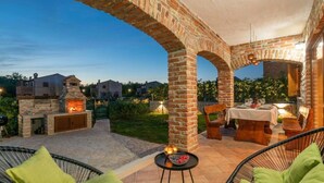 Une terrasse extérieure agrémentée d’arches en briques, d’un espace barbecue et de coins salon.