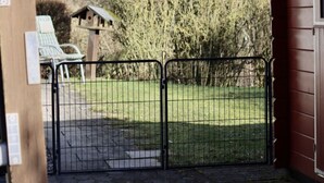 A gated entrance to a property with a wooden structure and a birdhouse in the background. - Deimann Modern Retreat (Schmallenberg)
