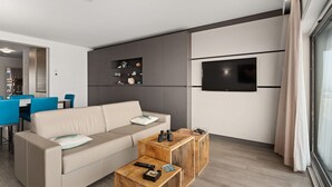 Un salon moderne avec un canapé, une table basse en bois et un téléviseur fixé au mur.