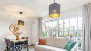 Ein modernes Wohnzimmer mit einer Couch, einem Esstisch und hängenden Pendelleuchten.