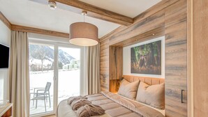 A bedroom with a bed, a window with a view of mountains, and a painting on the wall. - Golden Lodges Rauris Resort With Parking (Rauris)