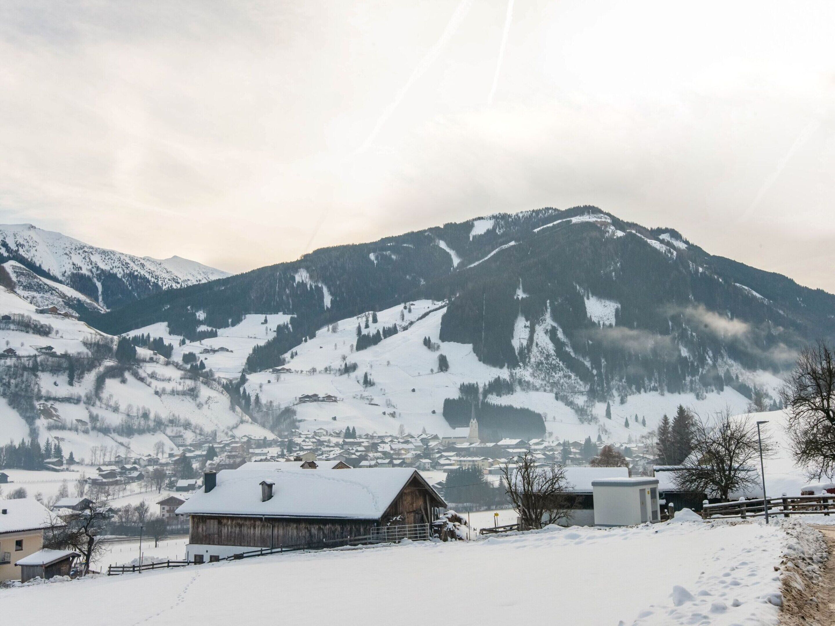 A snowy mountain landscape with a wooden cabin and a small building in the foreground.