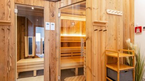 A wooden sauna room with benches, a shelf with storage bins, and a fire extinguisher on the wall. - Golden Lodges Rauris Resort With Parking (Rauris)