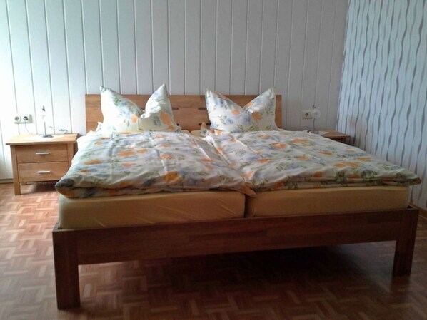 A bed with floral bedding, wooden headboard, and a nightstand with a lamp.
