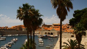 A harbor with boats docked, a stone wall, and buildings with red roofs. - Apartment in Konavle Region Gruda (Konavle)