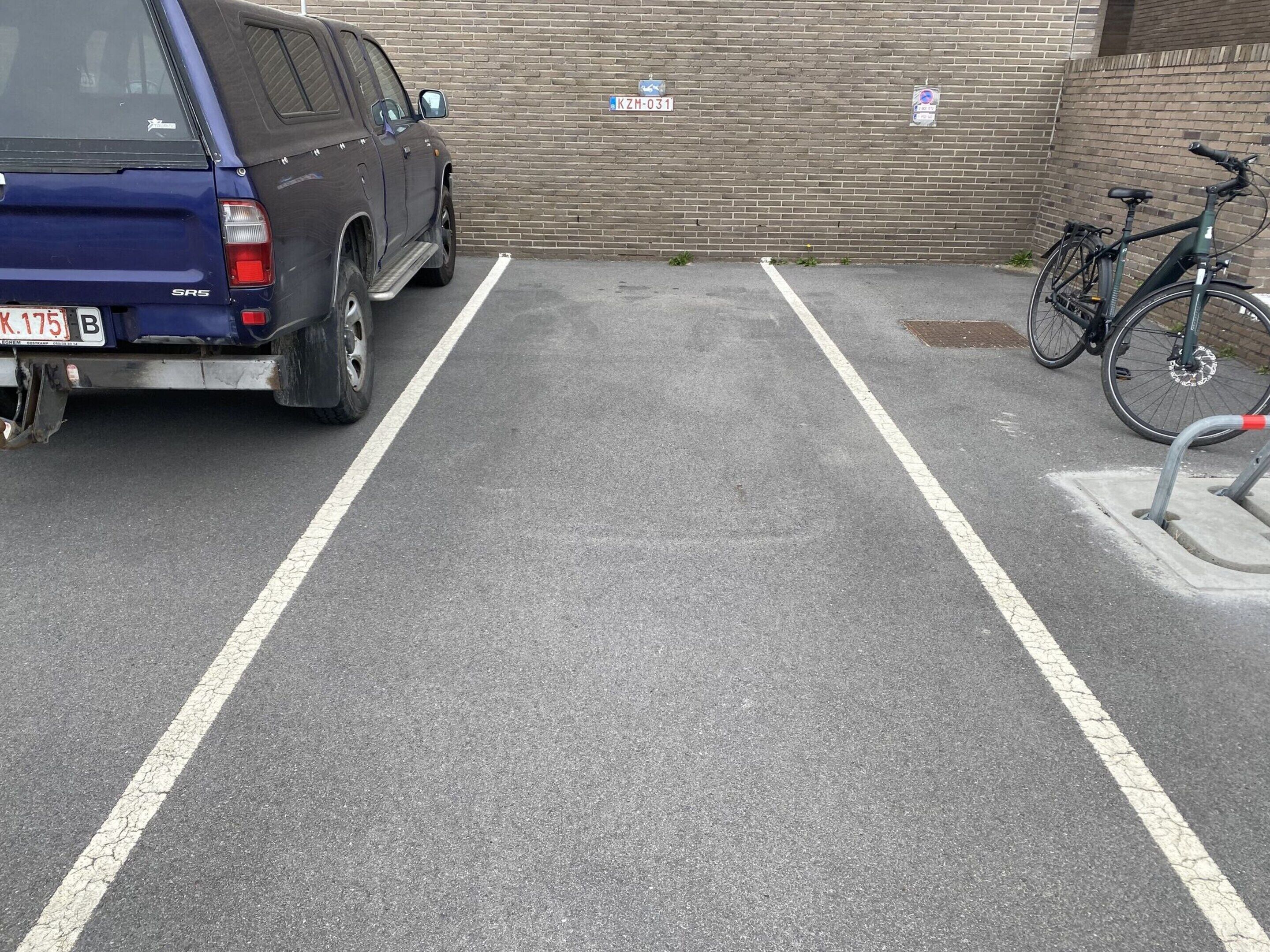 Un estacionamiento con una camioneta SUV azul y una bicicleta.