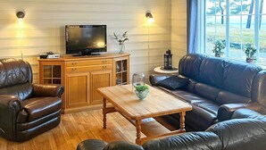 Una sala de estar con un sofá de cuero, una mesa de centro de madera y un televisor sobre un mueble de madera.