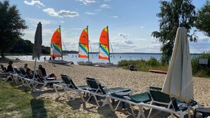 Ein Strand mit Liegestühlen und bunten Segelbooten im Hintergrund.