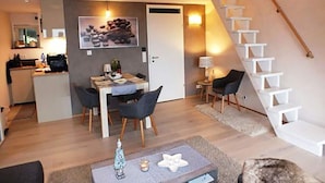 En modern lägenhet med matplats, kök och en trappa.