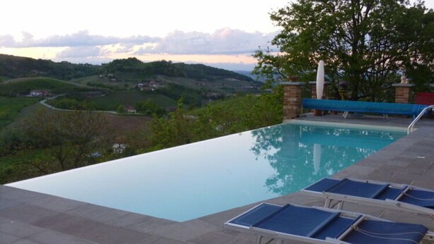 An infinity pool with a view of rolling hills and a tree in the background. - Apartment Milleluci 2 (Monforte d'Alba)