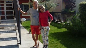 A man and a woman standing on a sidewalk next to a building with a metal gate. - Apartment Milleluci 2 (Monforte d'Alba)