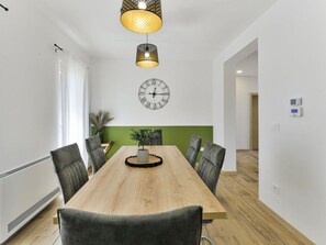 A modern dining room with a wooden table, six chairs, a wall clock, and pendant lighting. - With Pool, Jacuzzi and Sauna (Privlaka)