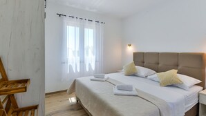 A bedroom with a bed, a nightstand, a wooden chair, and a window with curtains. - With Pool, Jacuzzi and Sauna (Privlaka)