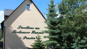 Ein Gebäude mit einem Schild, auf dem 'Landhaus am Frohnauer Kamm - Pension' steht.