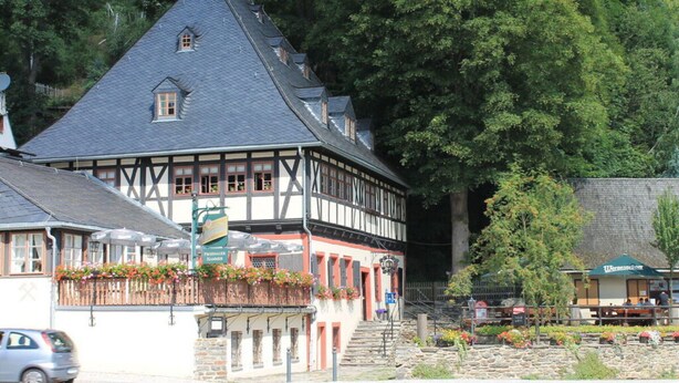 Ein traditionelles Fachwerkhäuschen mit steilem Dach, Steinmauerwerk und einem kleinen Fenster.
