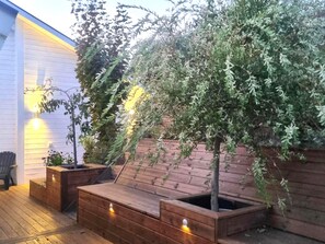 Una terraza de madera con jardineras integradas y un pequeño árbol.