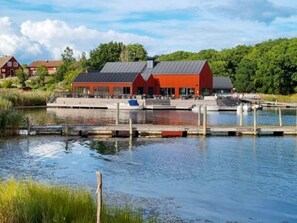 A waterfront property with a red building, dock, and surrounding greenery. - 5 Star Holiday Home in Ronneby (Ronneby)