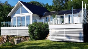 Une maison moderne dotée d’une grande baie vitrée, d’un balcon et d’un panneau solaire.