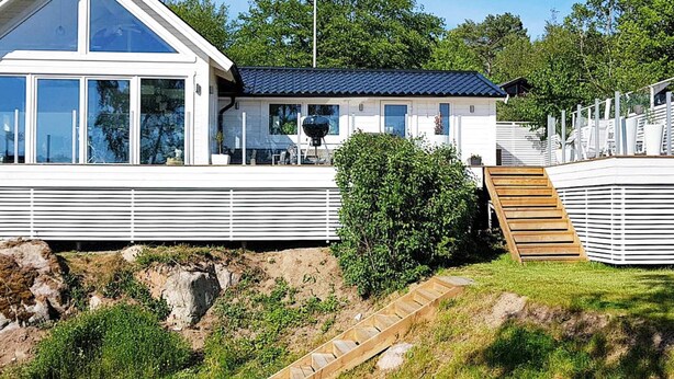 Een modern huis met een groot raam, een overdekte veranda en een houten terras.