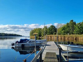 Un lago tranquilo con barcos amarrados, un muelle de madera y una orilla bordeada de bosque.
