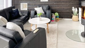 Een moderne woonkamer met een zwarte leren bank, een witte salontafel en een open haard.
