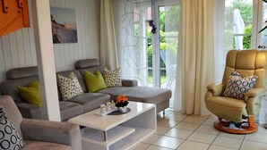 Ein modernes Wohnzimmer mit einem grauen Sofa, einem beigefarbenen Sessel und einem Couchtisch.
