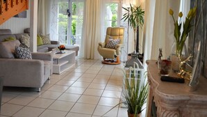 Ein geräumiges Wohnzimmer mit einer Sofagarnitur, einem Liegesessel, einem Couchtisch und einem Kamin.