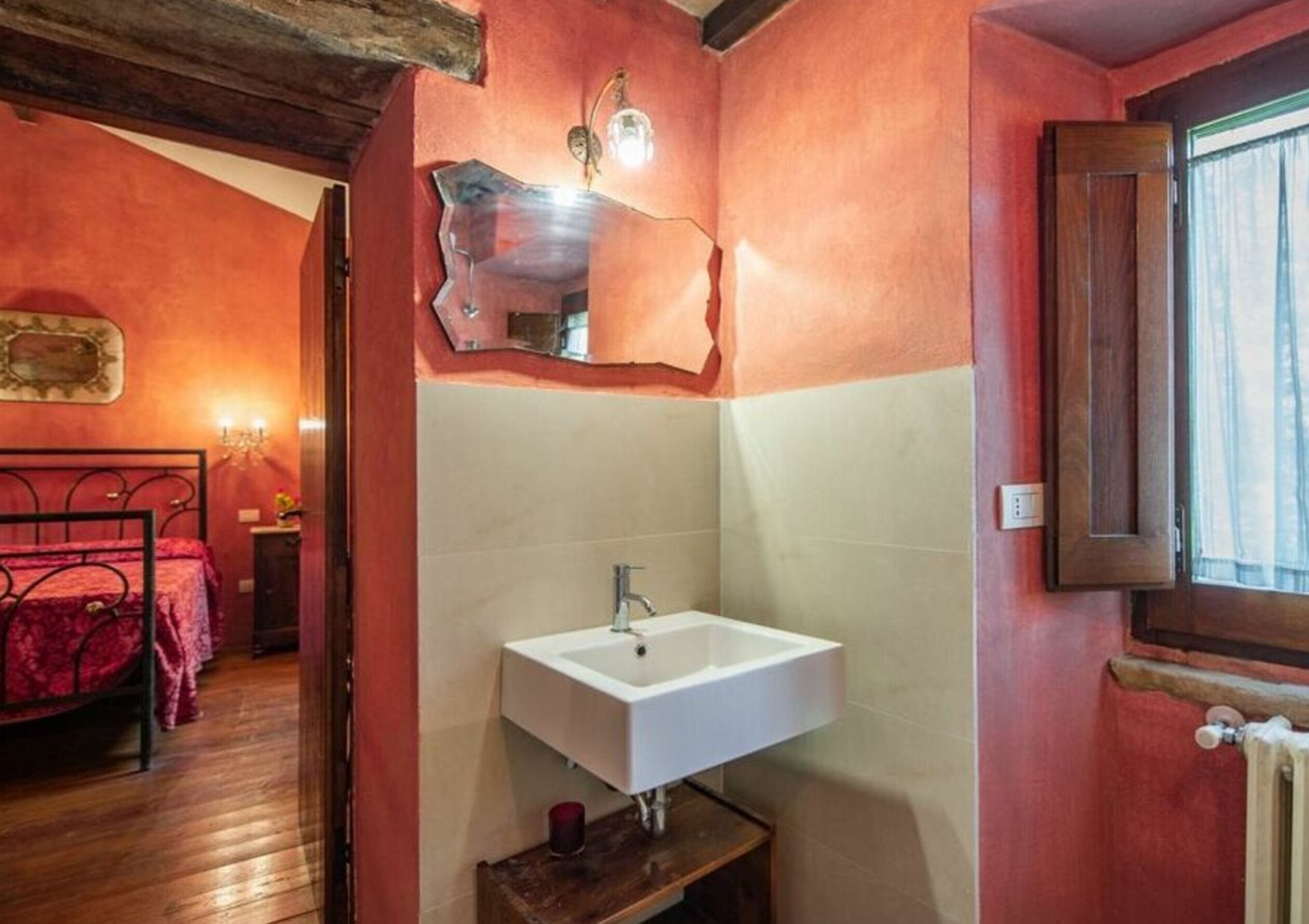 A bathroom with a white sink, a mirror, and a wooden floor.