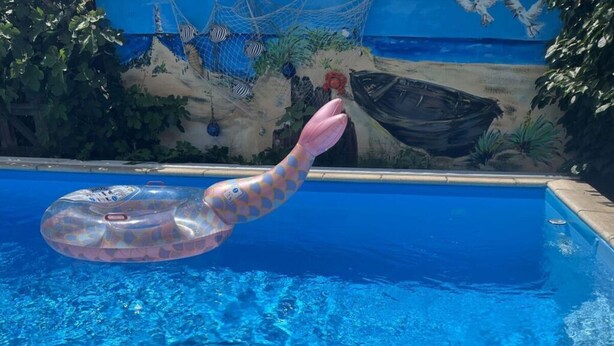 Une piscine dont l’eau est d’un bleu limpide, avec un objet flottant à la surface, orné d’un motif rose et jaune.